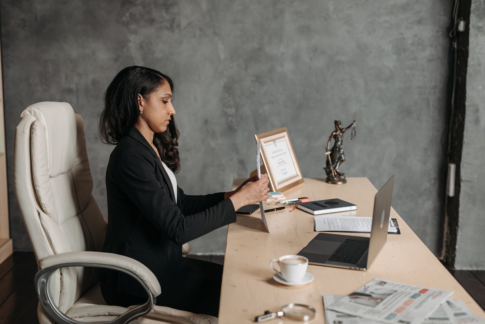 A businesswoman in formal attire works at a desk in a modern office.
