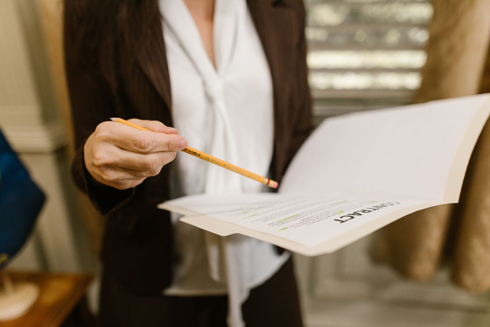 Una mujer de negocios señala con un lápiz un contrato durante una revisión en un entorno legal y corporativo.