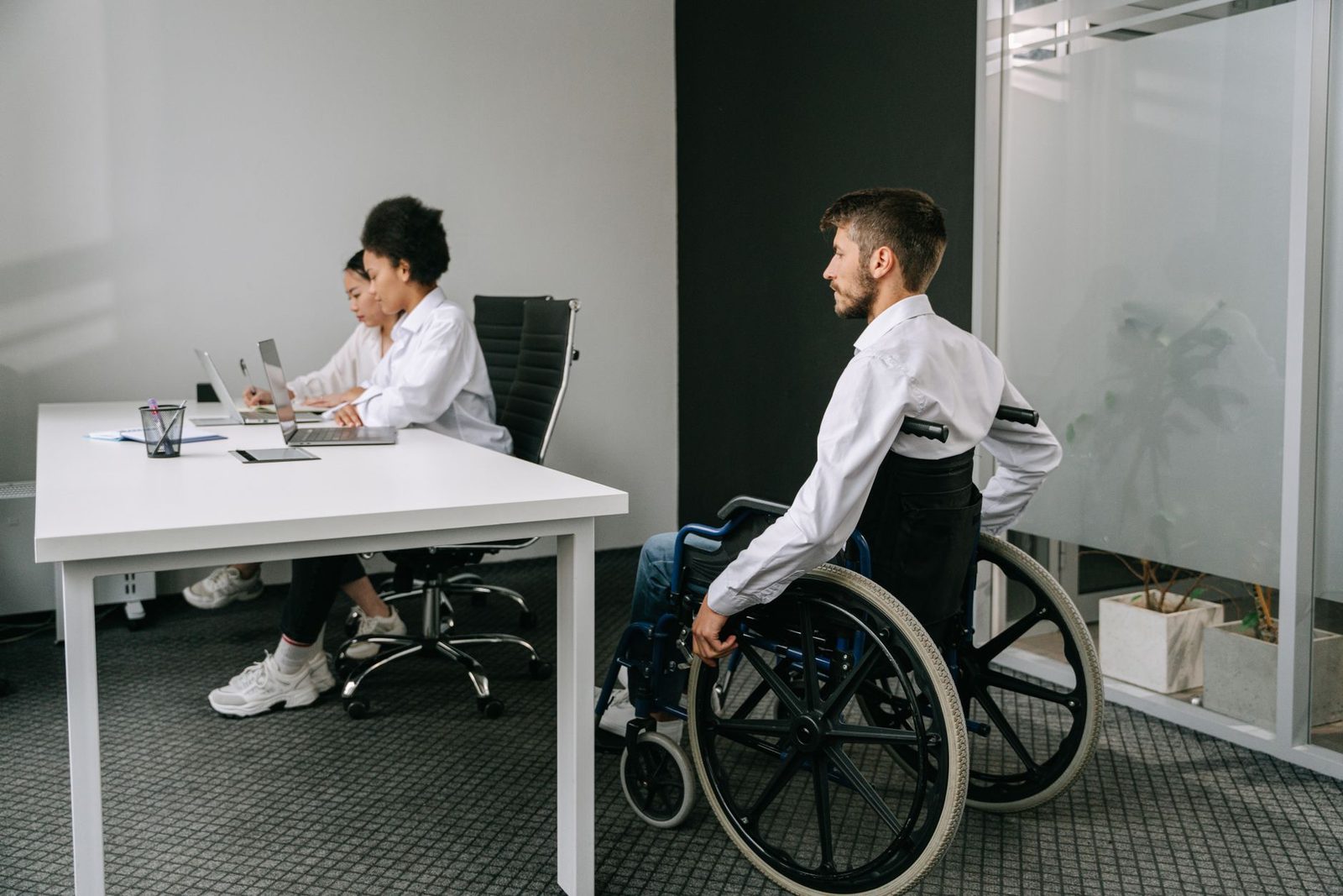 A diverse group of coworkers gathered around a table in a bright office during a meeting.