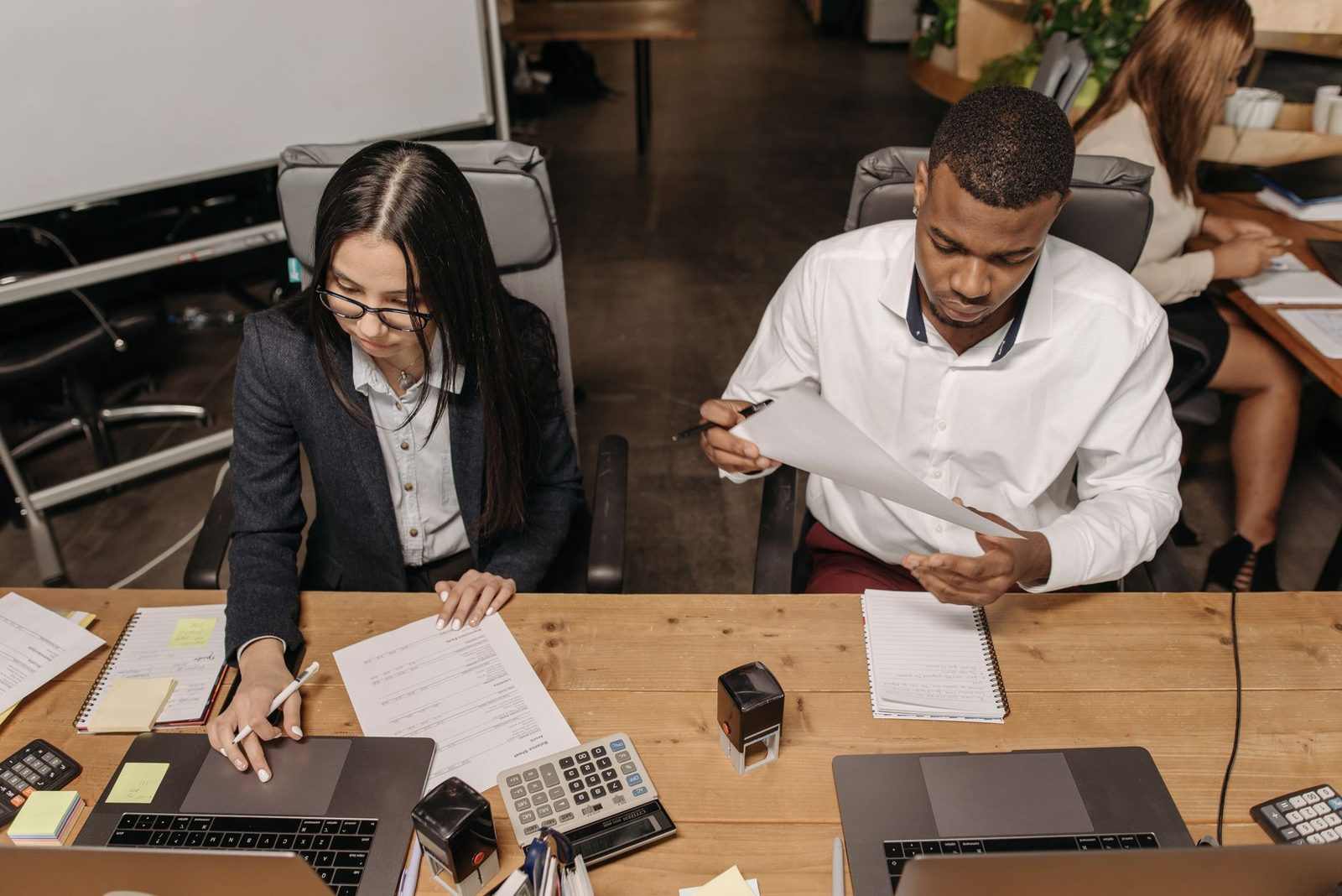 A diverse team of office workers reviews financial documents together at a table.