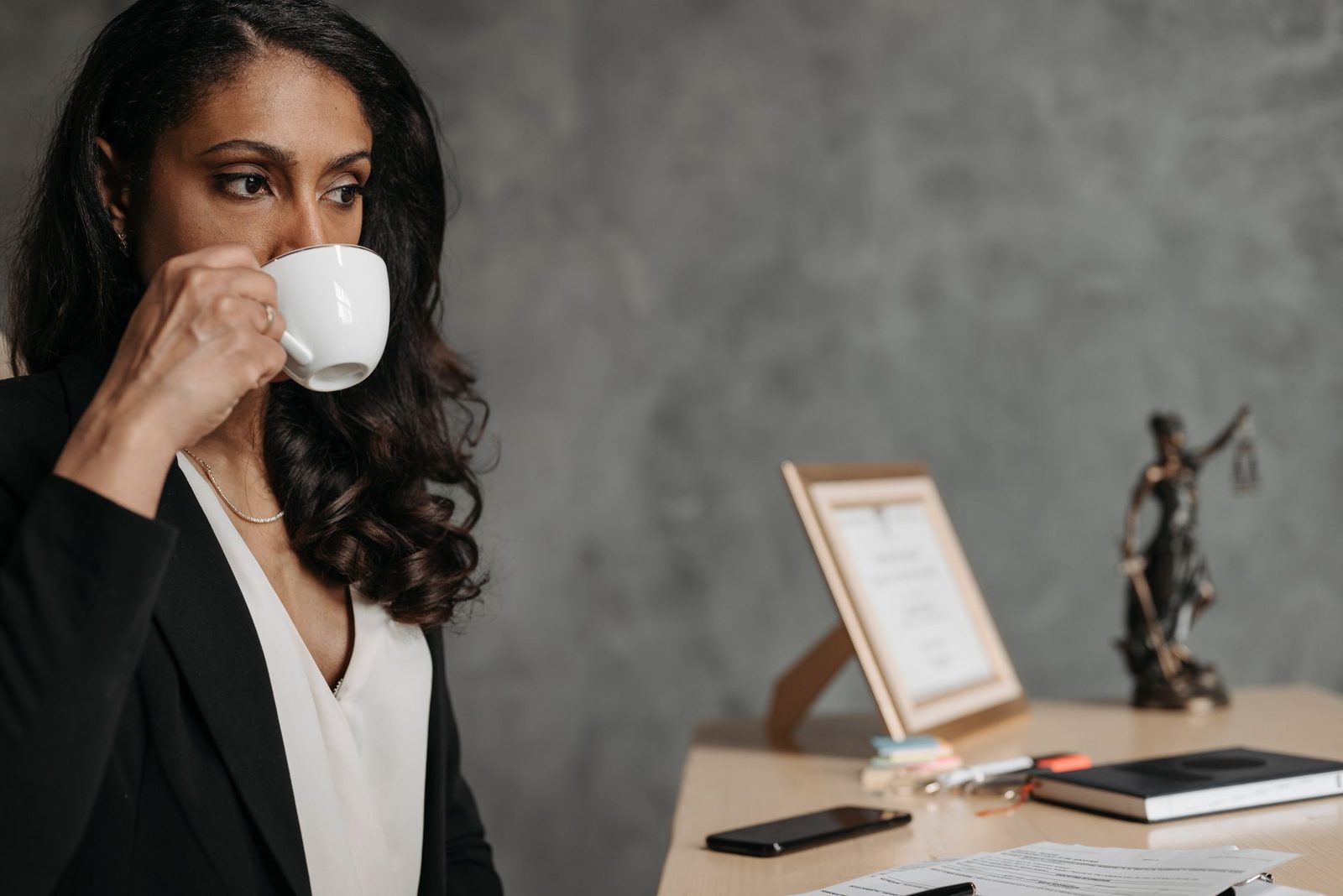 Una mujer profesional concentrada bebe café en su escritorio de oficina.