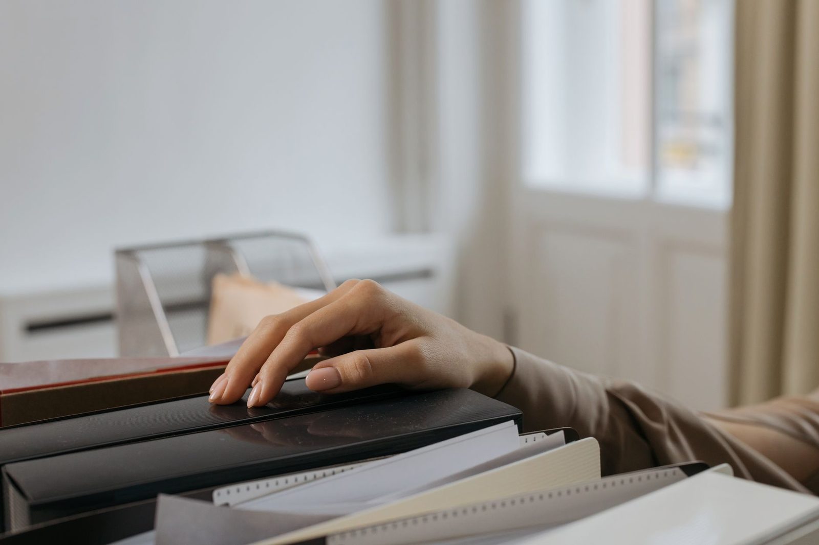 A hand reaching for office file folders in an indoor setting.