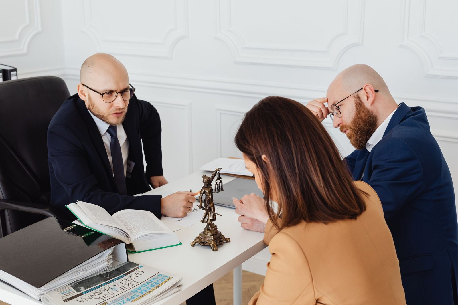 A lawyer in a modern office meets with clients in a serious discussion about a business deal.