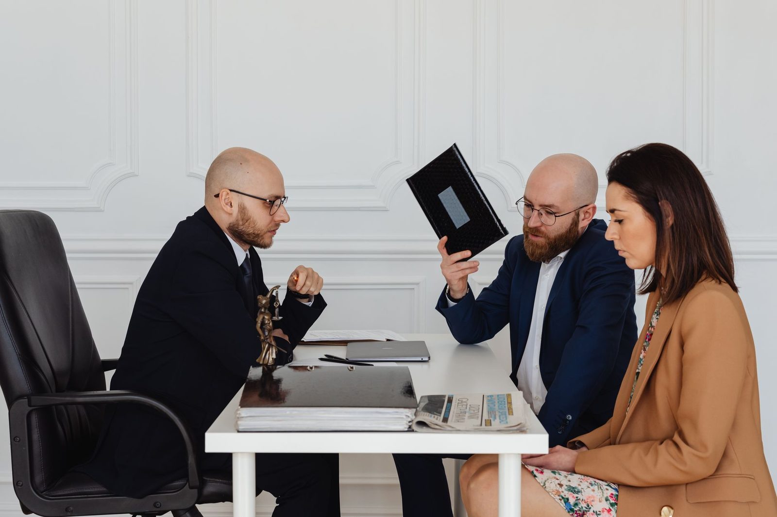 A lawyer and a couple discussing documents at an office desk.