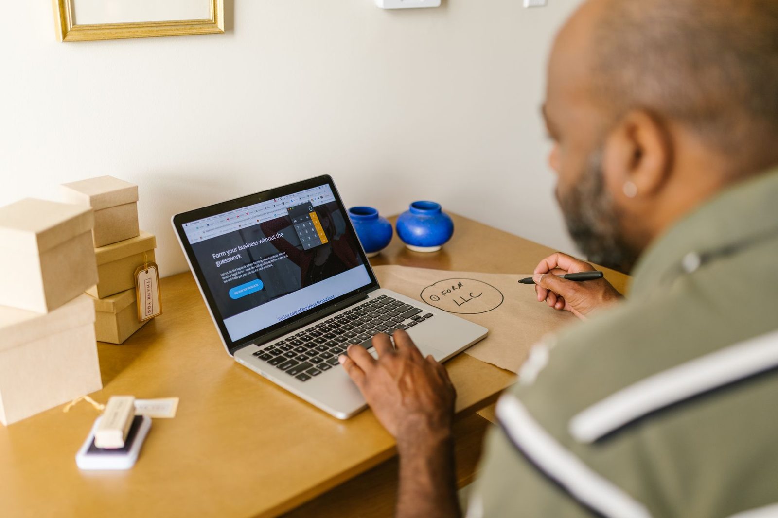 A person sits at a desk working on a laptop while planning their business.