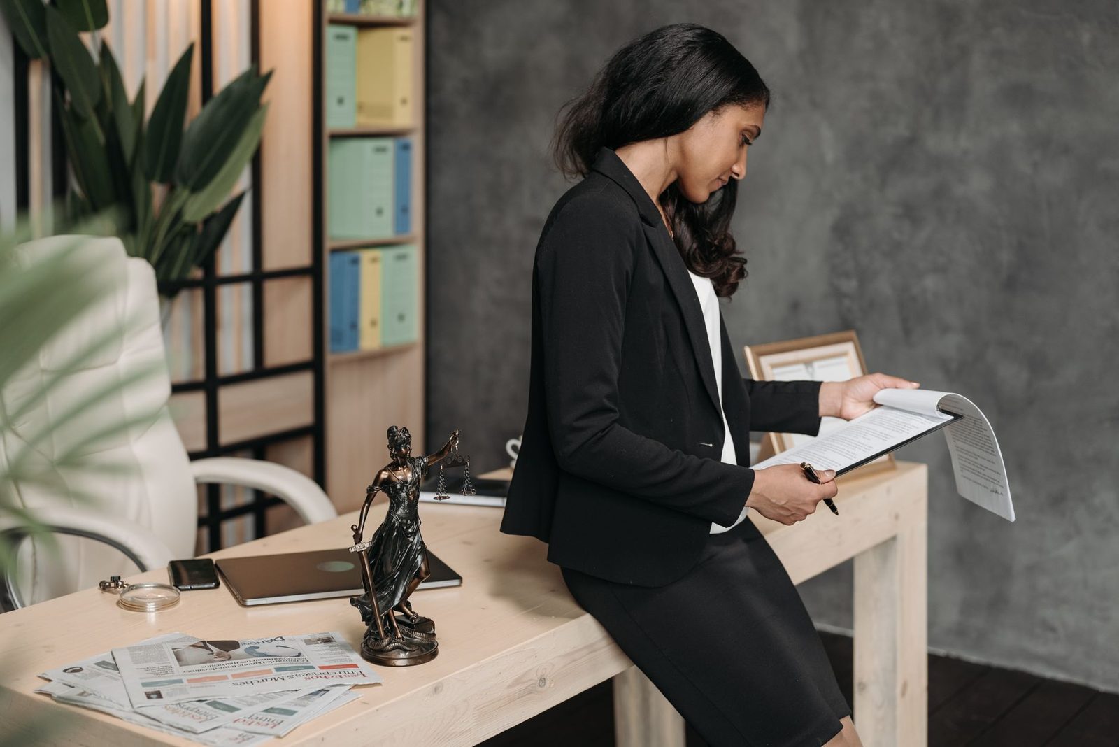 Una mujer profesional con traje de negocios revisa documentos legales en un escritorio de oficina.
