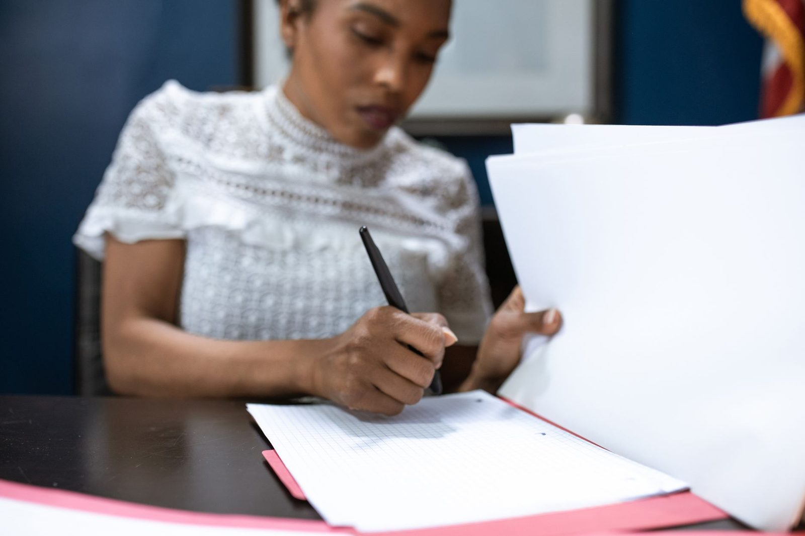 Una mujer firma documentos en un escritorio de una oficina elegante.