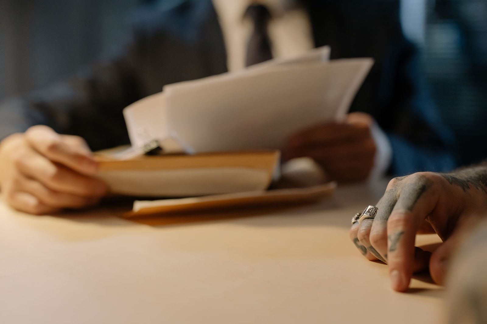 Personas de negocios revisando documentos en un escritorio, enfocadas en sus manos y papeles.