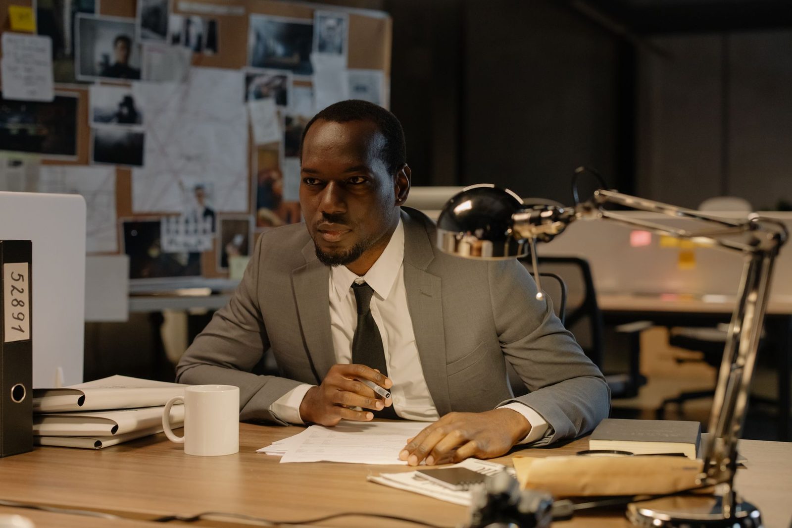 Businessman in a suit concentrating while reviewing documents at a desk.
