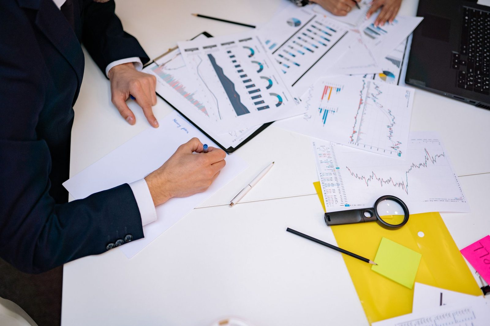 Close-up of a cluttered desk covered with financial charts, graphs, and reports.