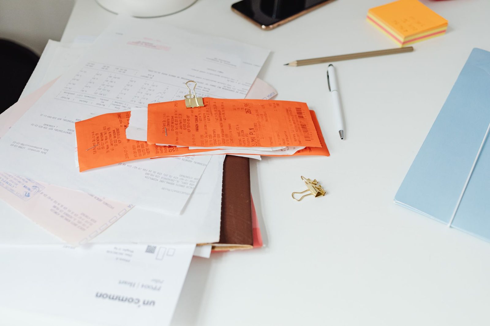 Primer plano de un escritorio ordenado con recibos, documentos y papelería de oficina dispuestos sobre la mesa.