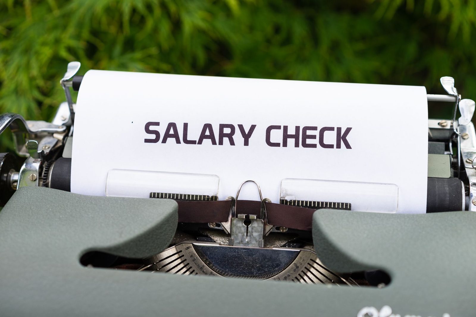 Close-up of a vintage typewriter with the words "Salary Check" typed on paper.