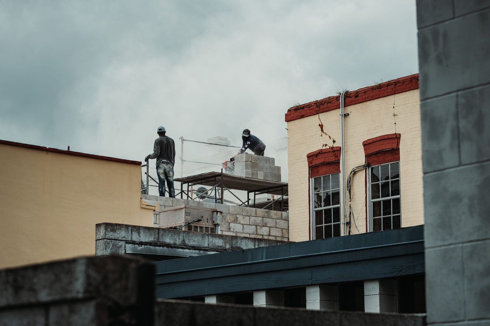 Workers laying bricks on a daytime urban construction site.