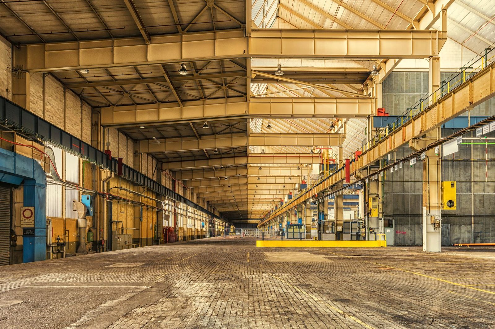 Interior vacío de una bodega industrial con vigas de acero expuestas, techos altos y amplio espacio abierto.