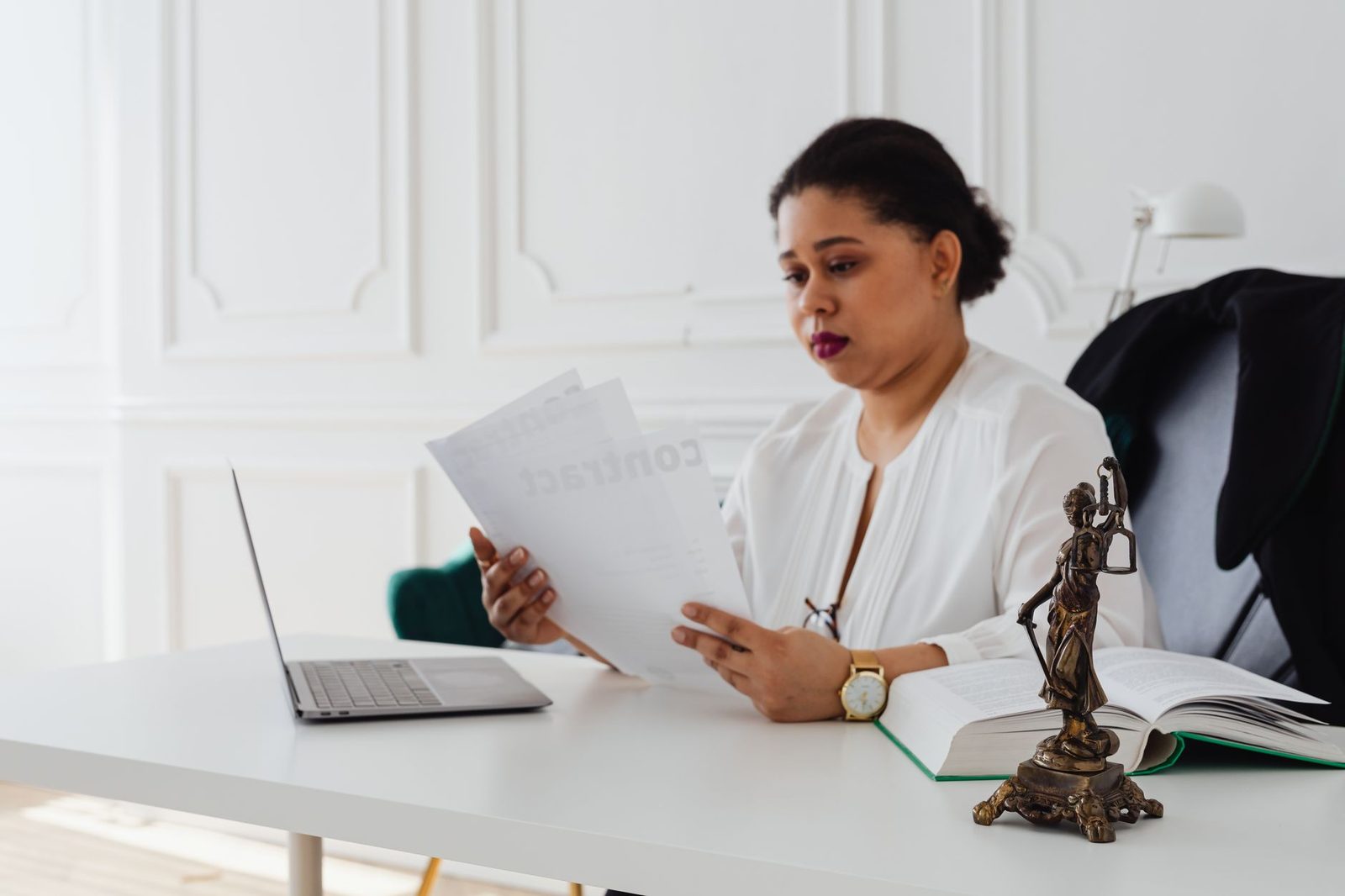 Female attorney reviewing legal documents at office desk.