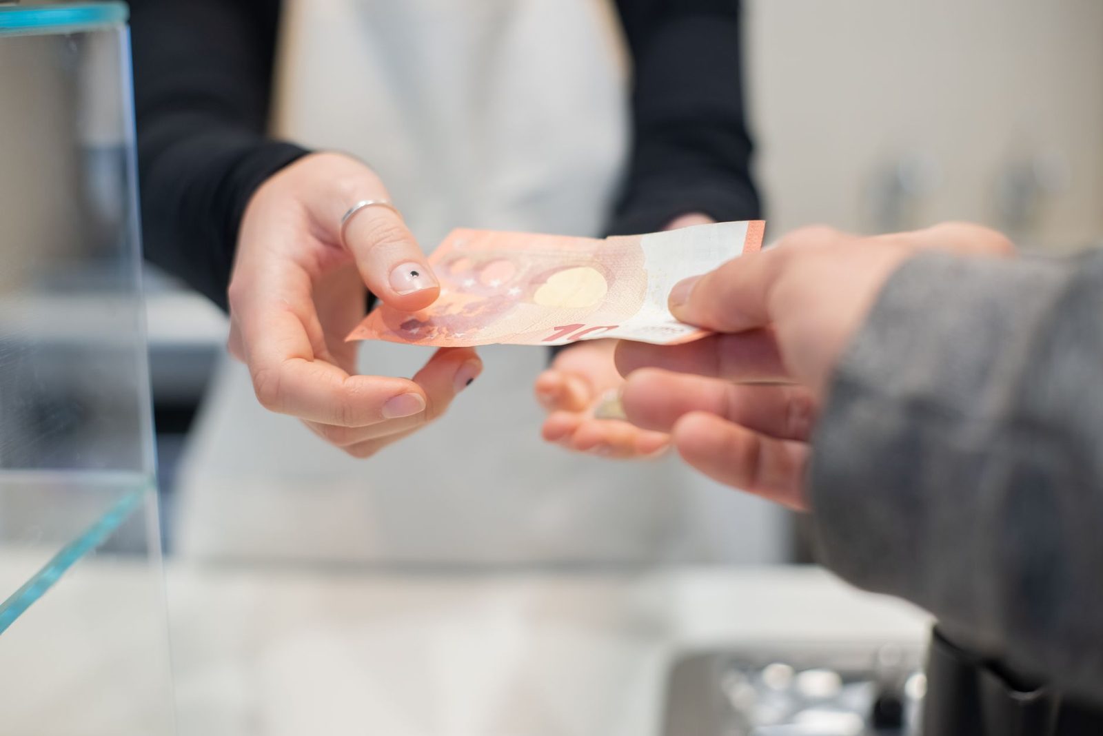 Hands exchanging cash across a café table in a close-up business transaction.