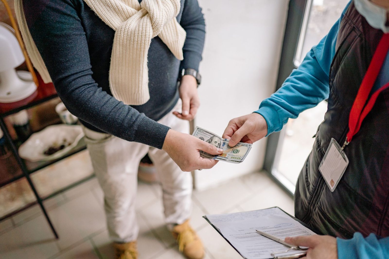 Hands passing cash across a table during an indoor transaction, showing the payment being exchanged.