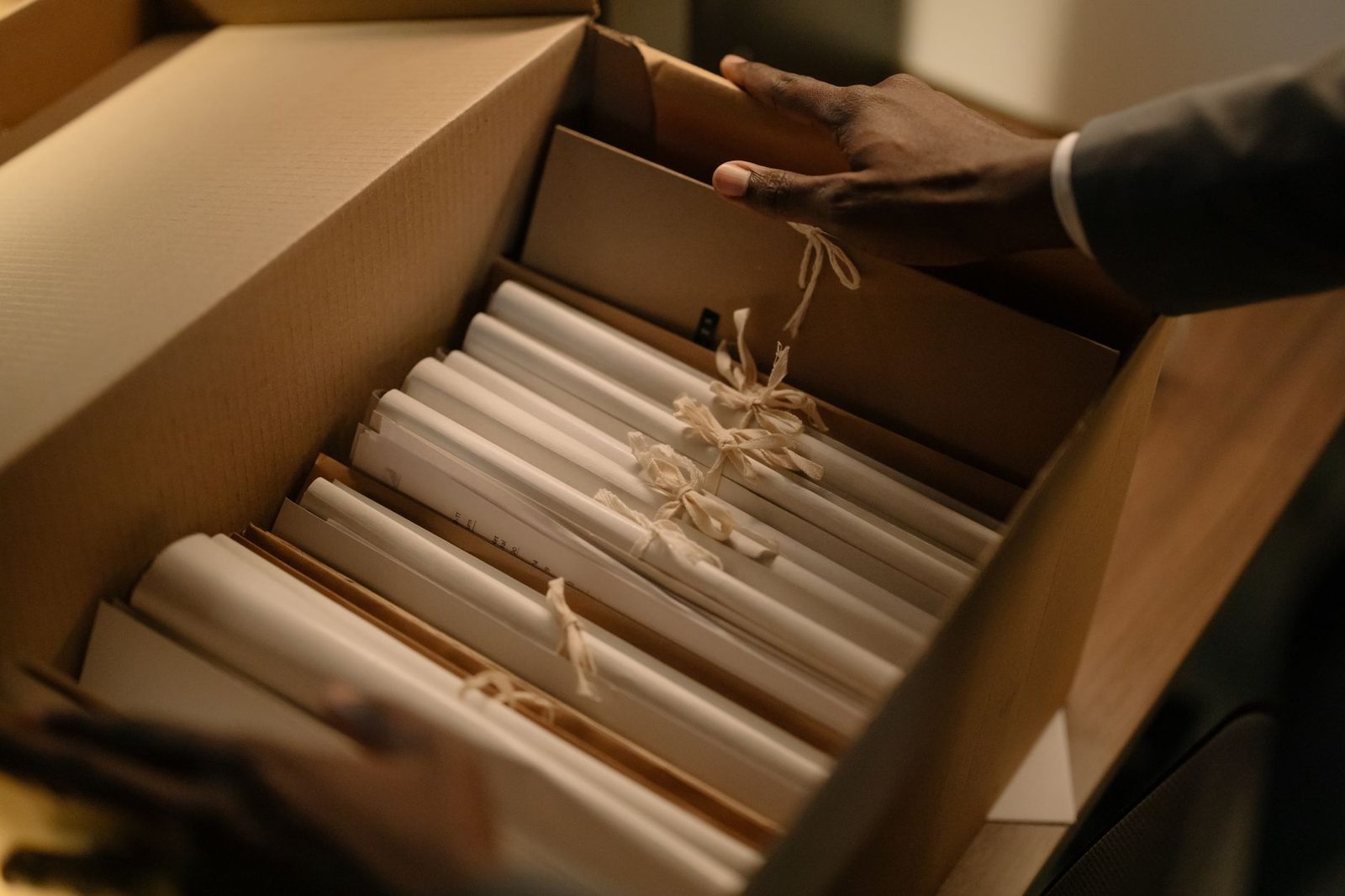 Manos clasificando expedientes legales en una caja de cartón.