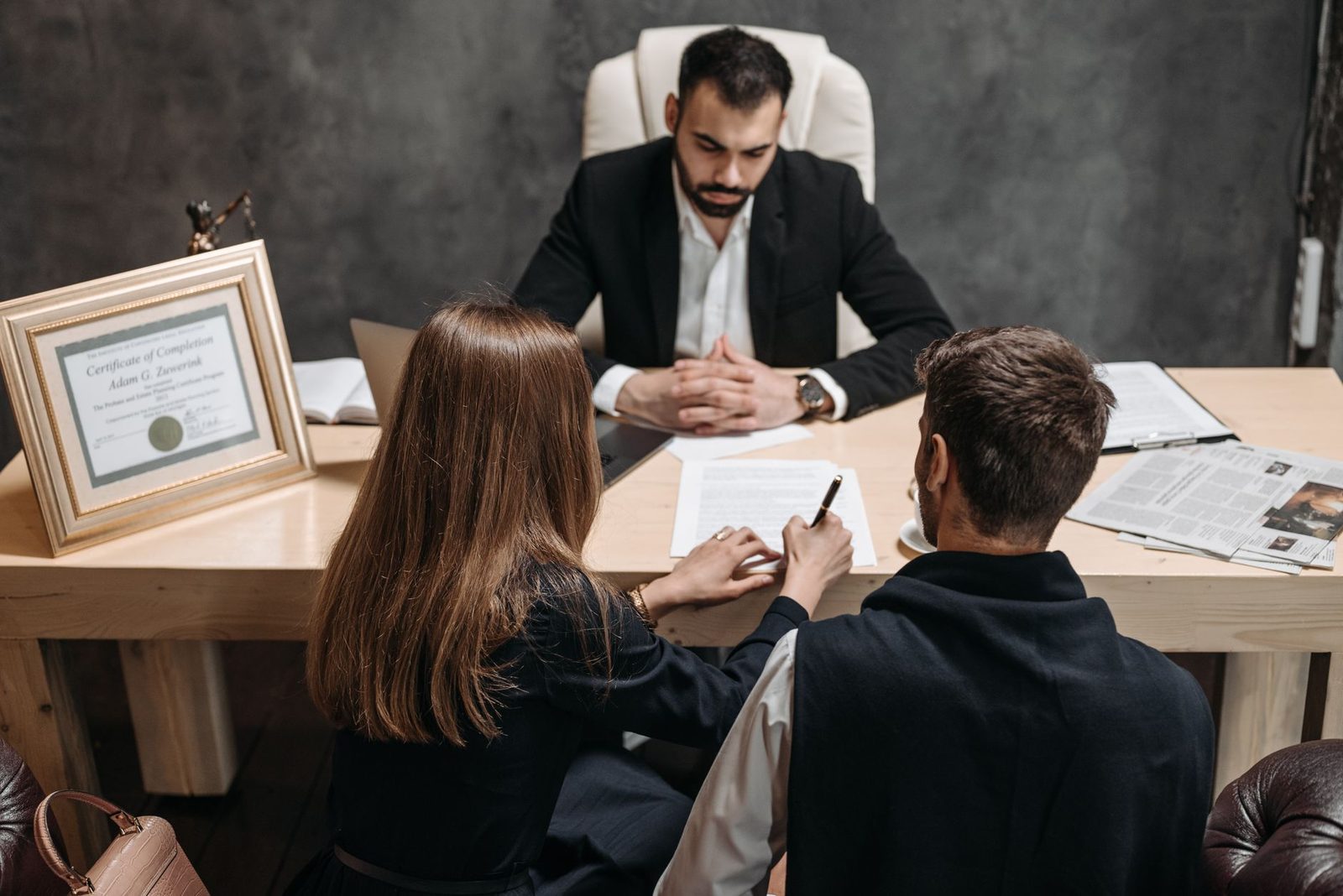 Lawyer reviewing legal documents with clients at office desk.