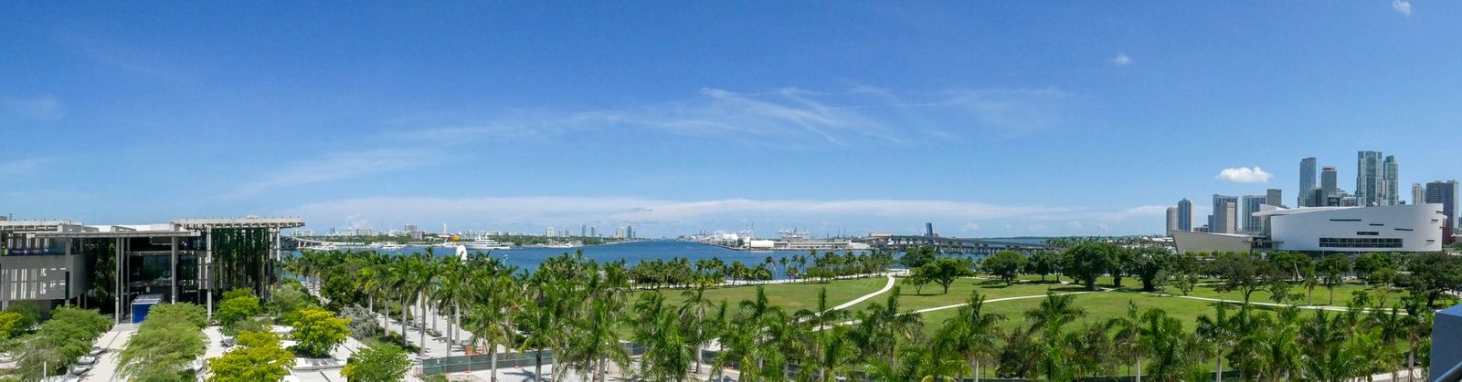 Horizonte de Miami sobre parques verdes bajo un cielo azul despejado.