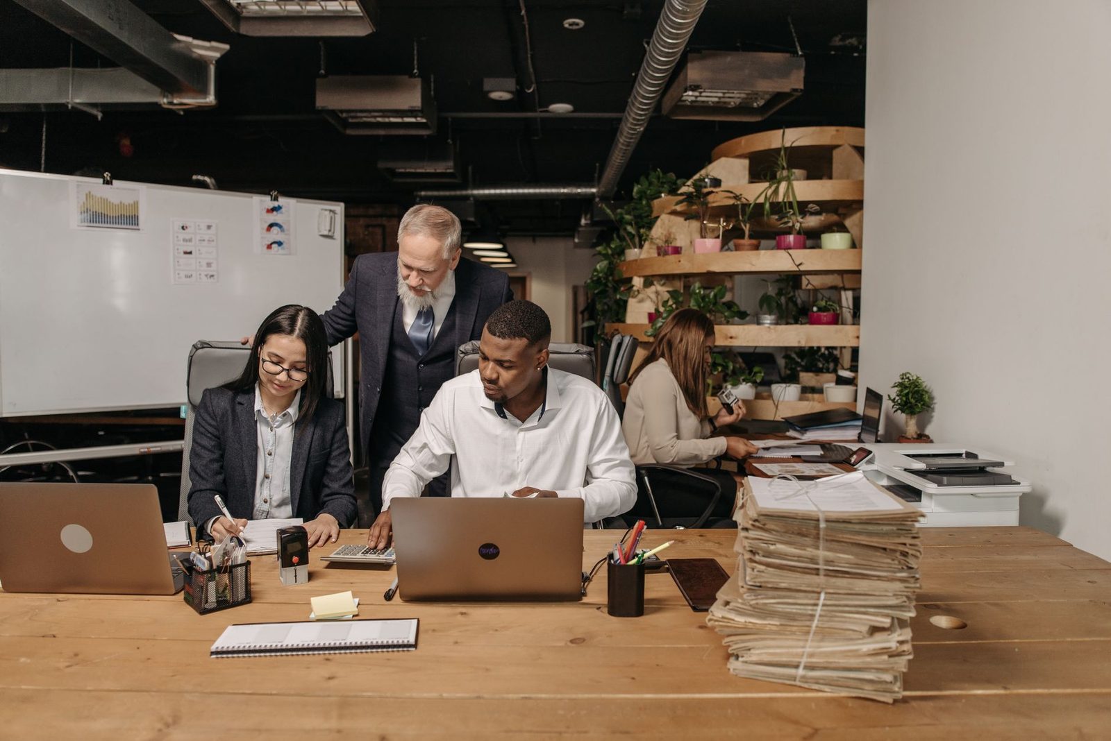 Professionals collaborating at desks with documents and laptops in a modern office.