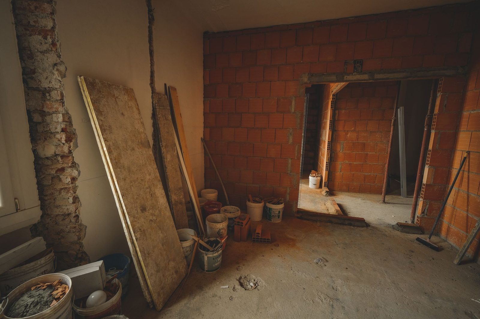 Red brick wall under construction, with tools and building materials scattered across a renovation site.