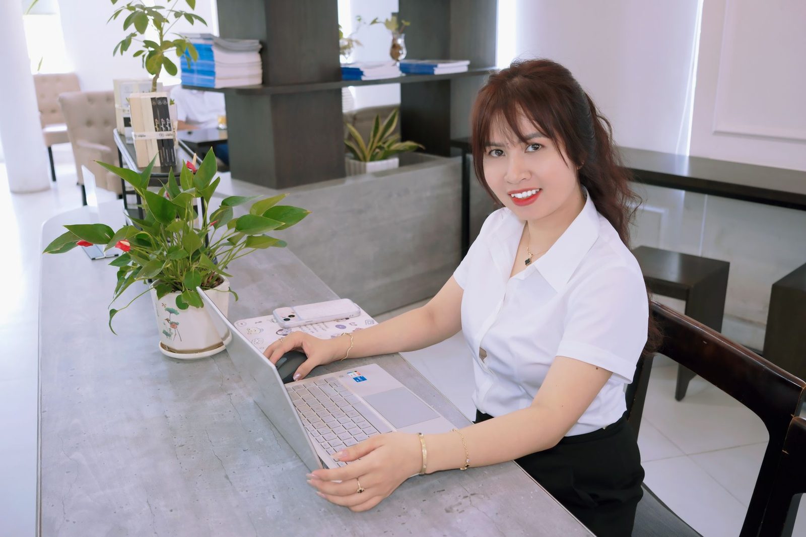 Smiling woman works on a laptop at a modern office desk.
