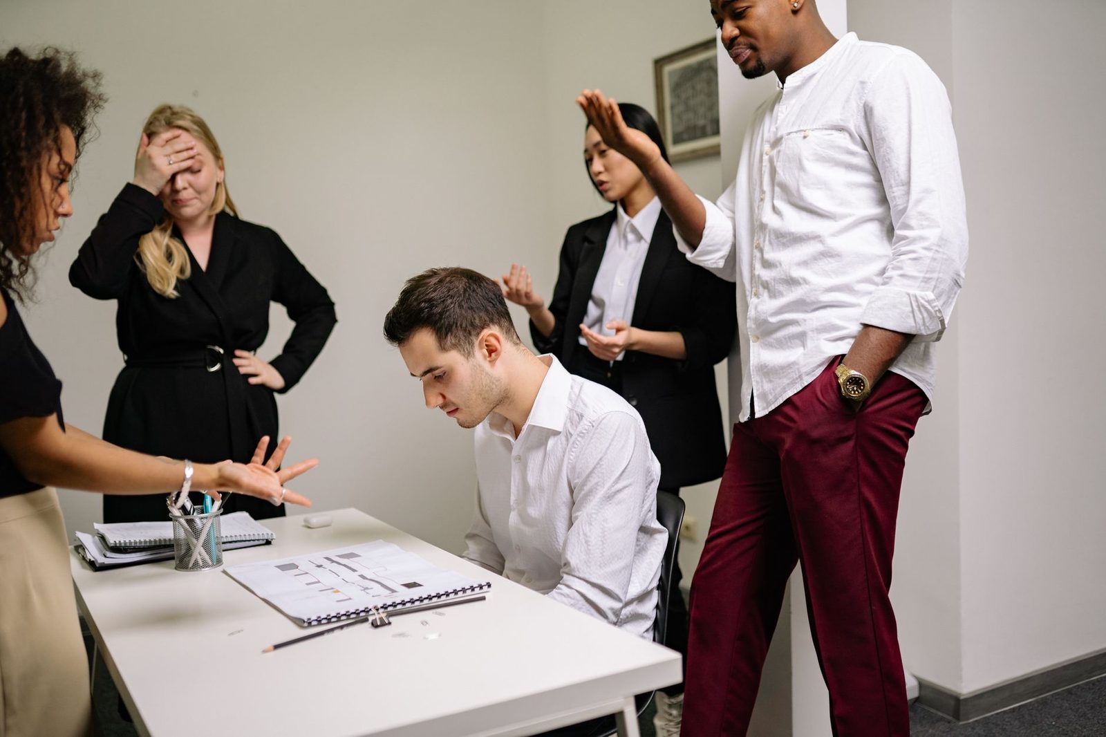 Two colleagues sit across a conference table in a tense discussion, illustrating a workplace conflict over an employee problem.