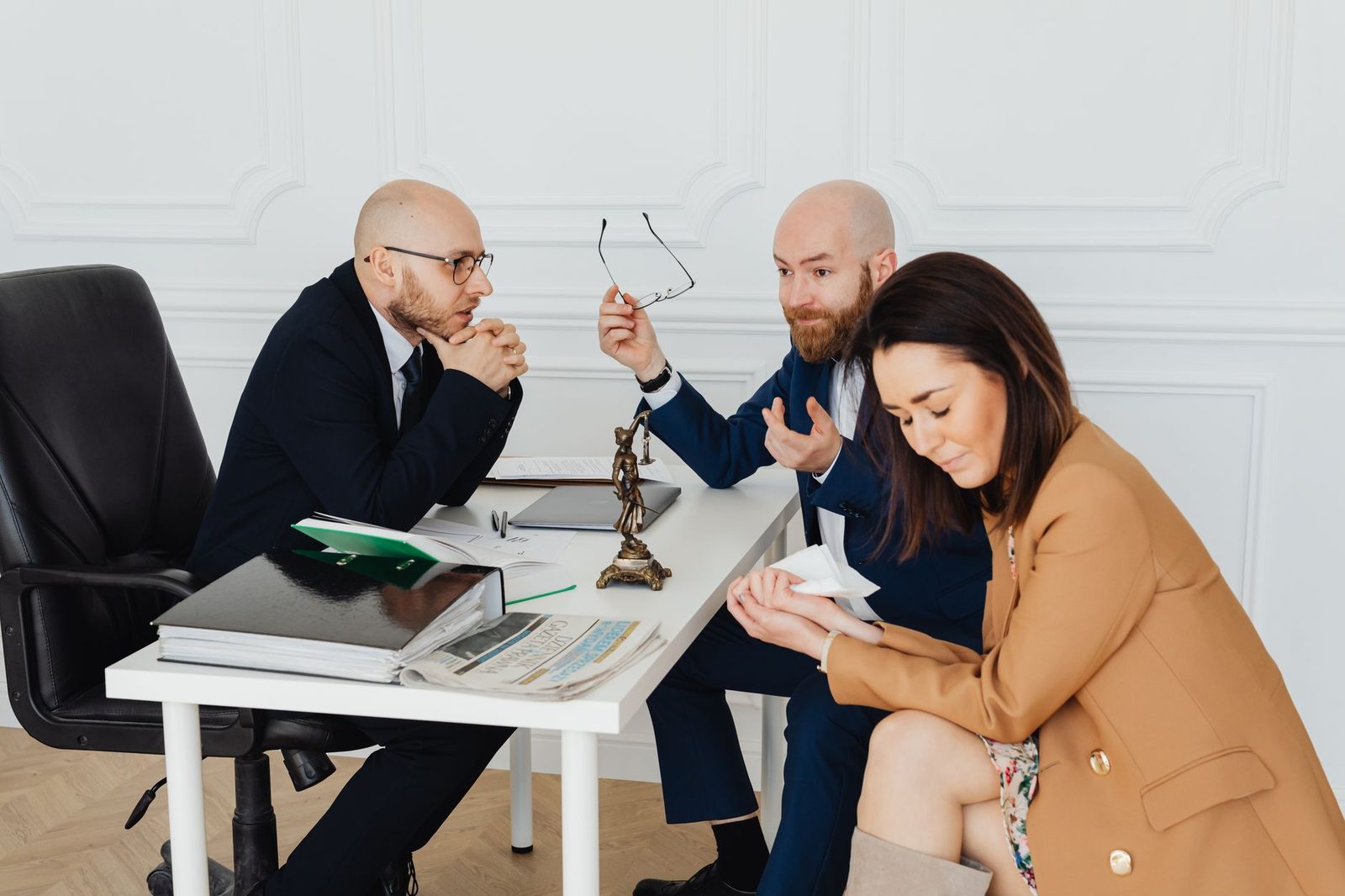 Two lawyers meet with frustrated clients at a conference table during a tense mediation session in an office.