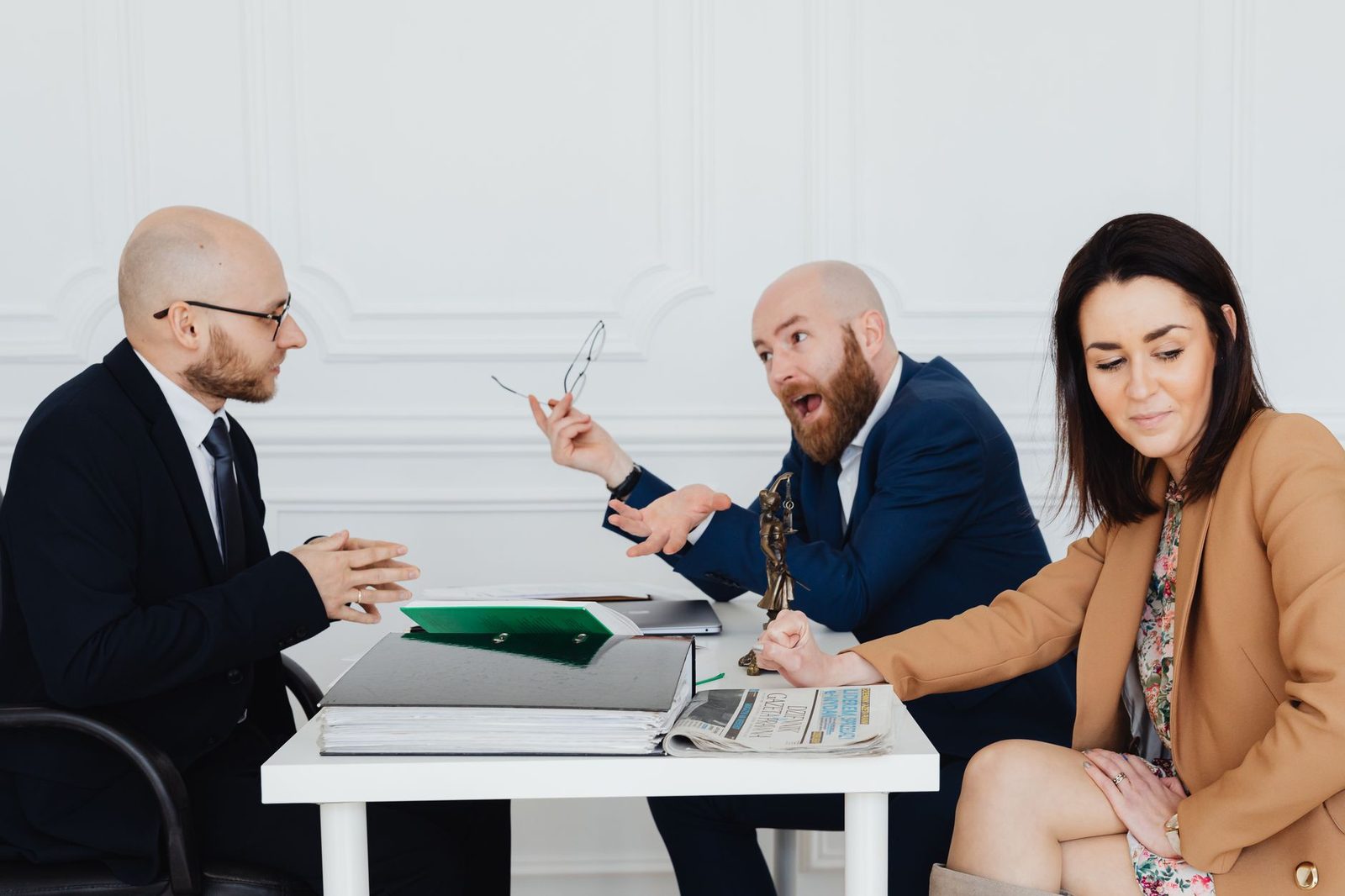 Two men and a woman argue across a conference table in a modern corporate office.