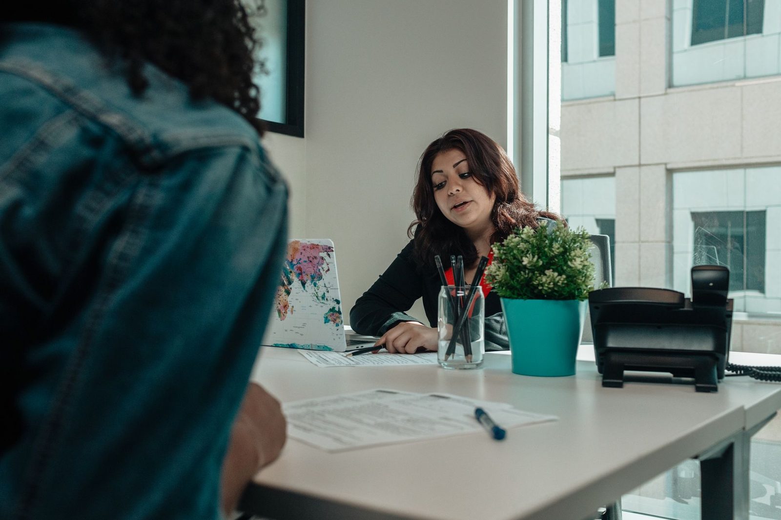 Two people in an office reviewing paperwork together across a desk.