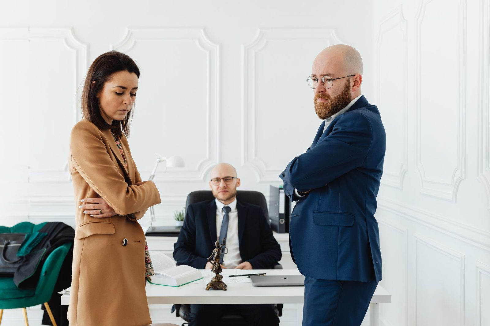 Un hombre y una mujer con traje de negocios sentados frente a frente en una mesa de conferencias durante una mediación.