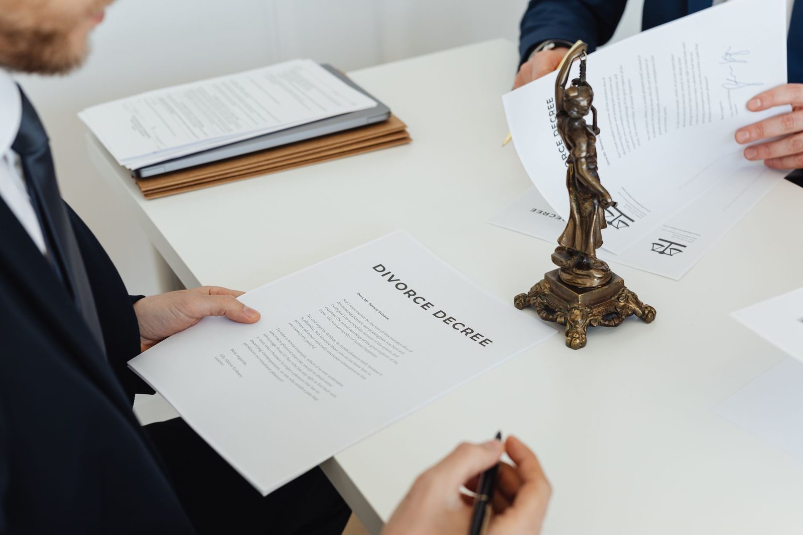 Two professionals in business attire review divorce decree documents across a desk during a legal negotiation.