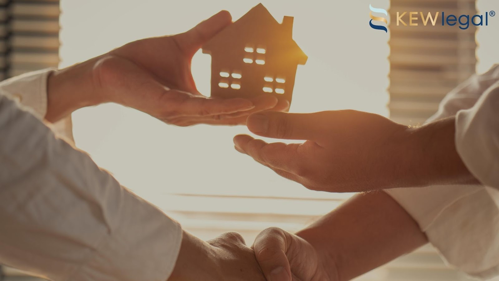 Hands exchanging small house model in sunlight.