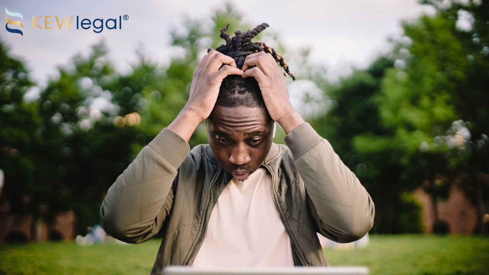 Person looking stressed at laptop outdoors.