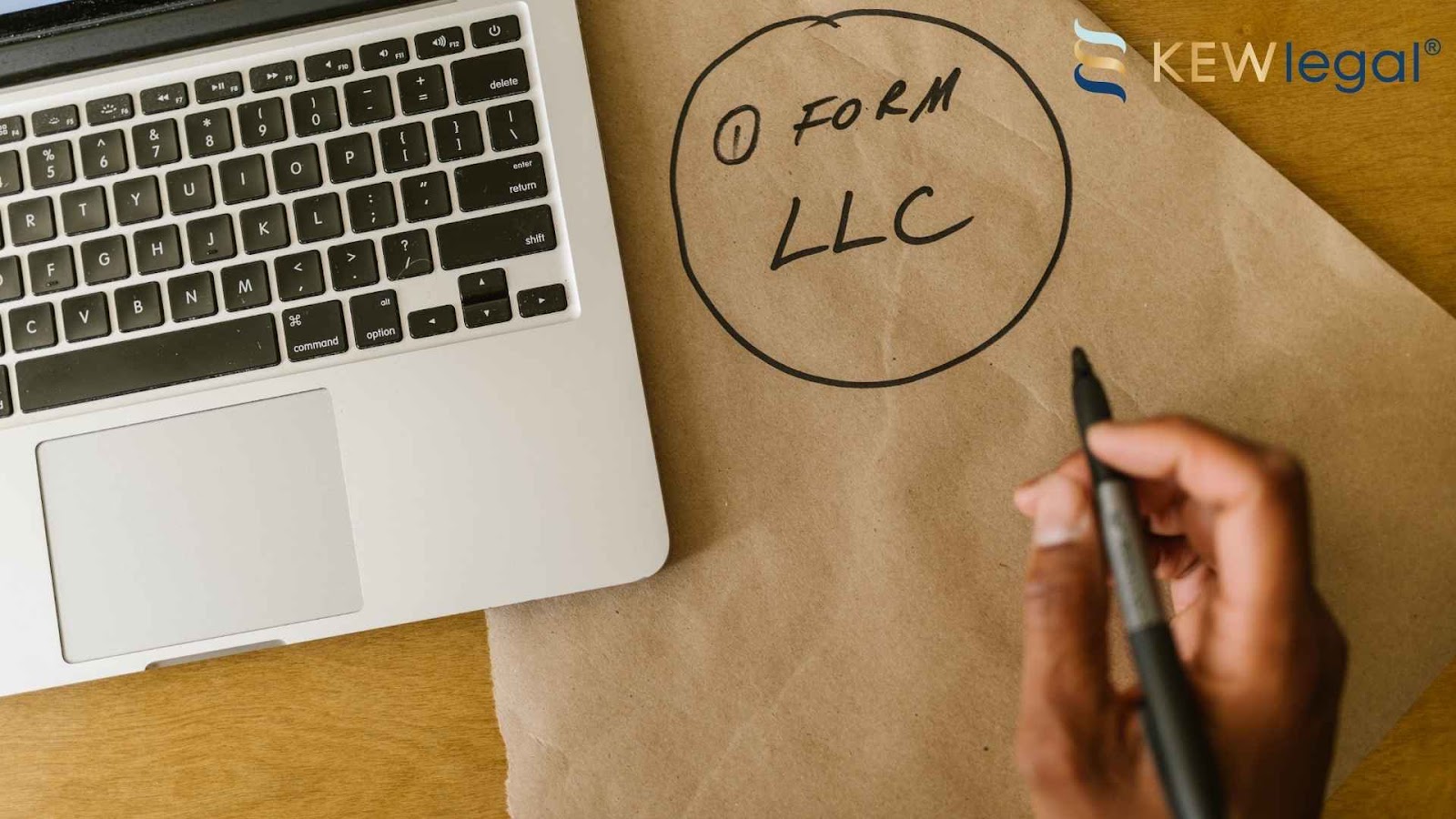 Person planning LLC formation on paper with laptop.