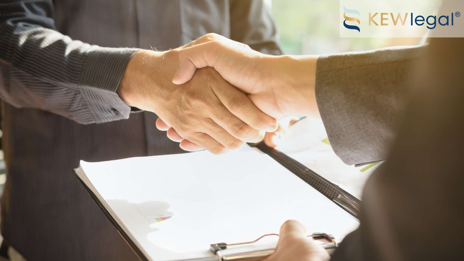 Handshake over business documents in office setting.