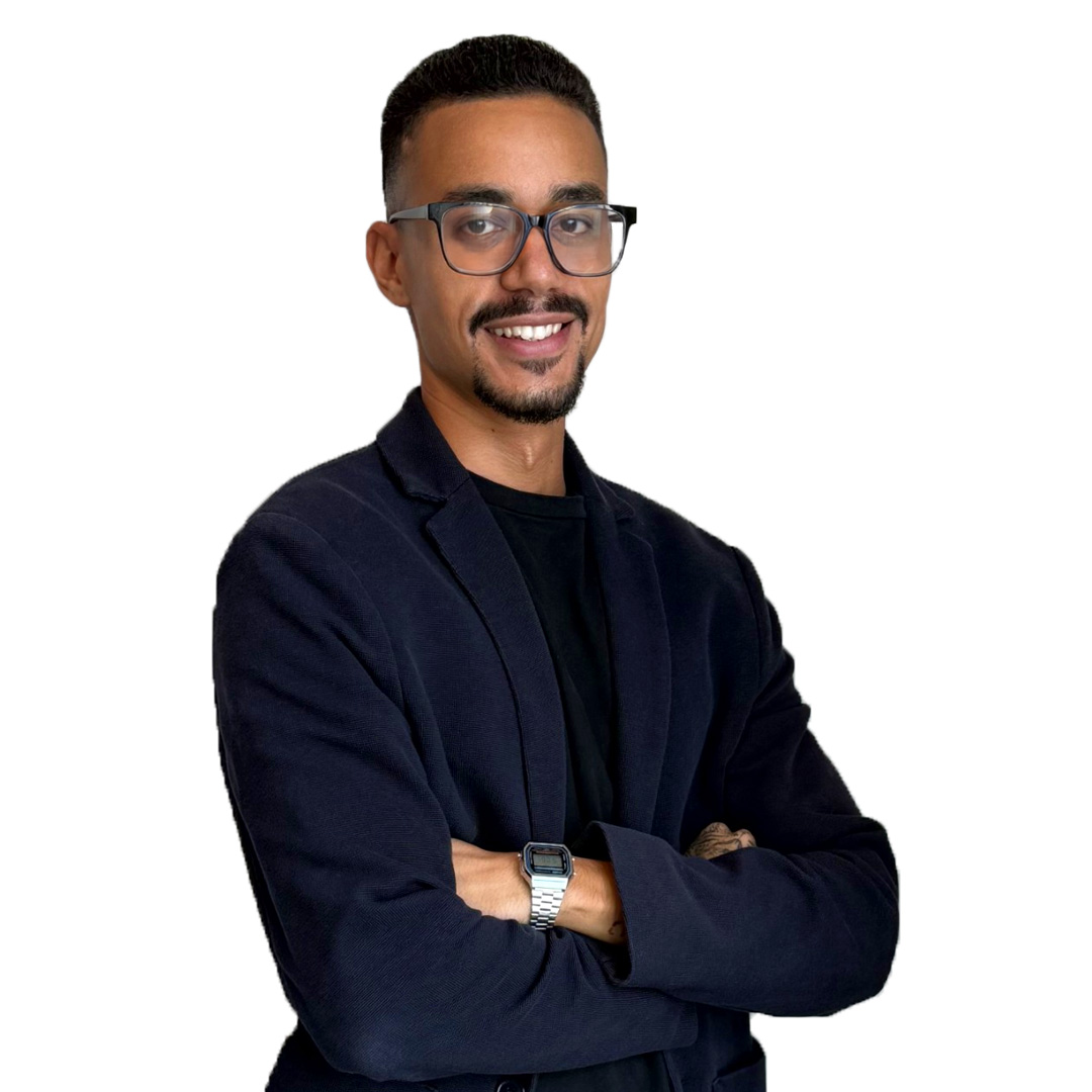 Smiling person in a dark blazer with glasses.