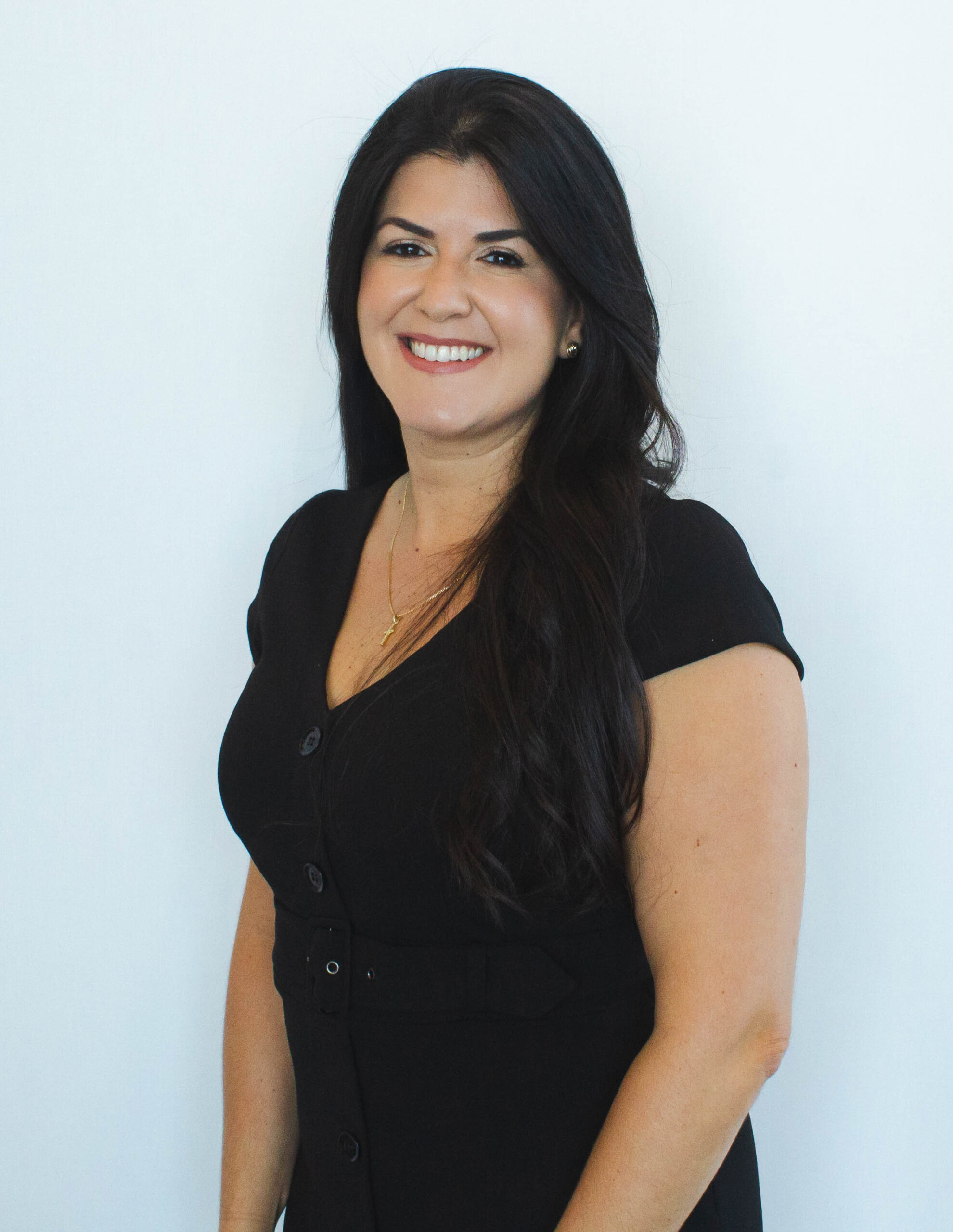 Smiling woman in black dress against white background.